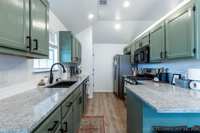 1113 S Spinnaker Dr, Oologah, OK 74053 - kitchen featuring stainless steel appliances, green cabinets, light wood-style flooring, vaulted ceiling, and decorative backsplash