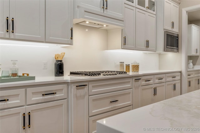 4708 S Sequoia Ave, Broken Arrow, OK 74011 - kitchen featuring appliances with stainless steel finishes, light countertops, white cabinetry, custom range hood, and glass insert cabinets