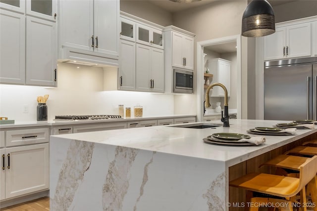 4708 S Sequoia Ave, Broken Arrow, OK 74011 - kitchen featuring built in appliances, white cabinetry, a kitchen breakfast bar, glass insert cabinets, and an island with sink