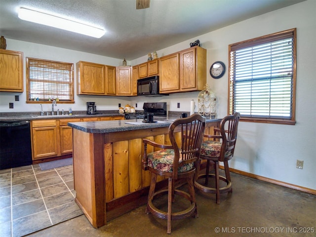447 Pink Gladiola St, Broken Bow, OK 74745 - kitchen with black appliances, dark countertops, a peninsula, a kitchen breakfast bar, and brown cabinets