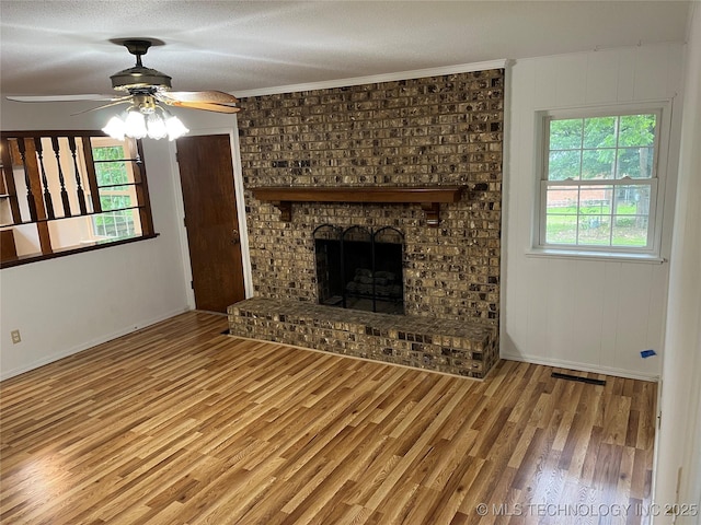 1918 E 14th, Ada, OK 74820 - unfurnished living room featuring wood finished floors, ceiling fan, a brick fireplace, a textured ceiling, and crown molding