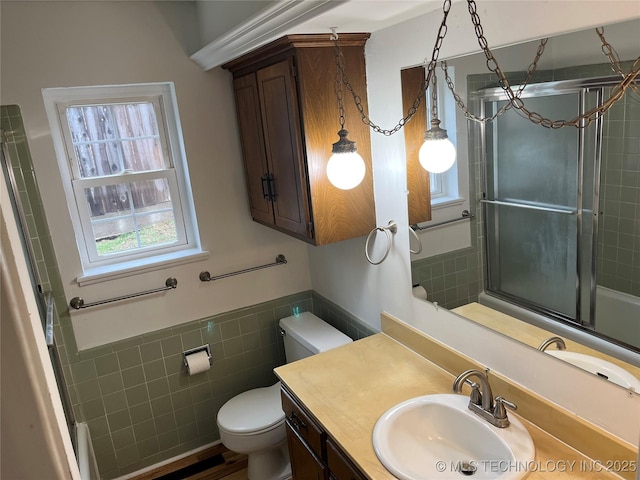 1918 E 14th, Ada, OK 74820 - bathroom featuring tile walls, vanity, enclosed tub / shower combo, and wainscoting