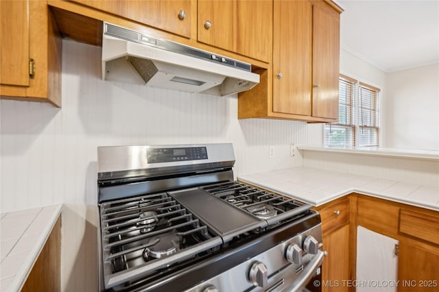 2178 S 76th E Ave, Tulsa, OK 74129 - kitchen featuring stainless steel range with gas stovetop, under cabinet range hood, tile countertops, ornamental molding, and brown cabinetry