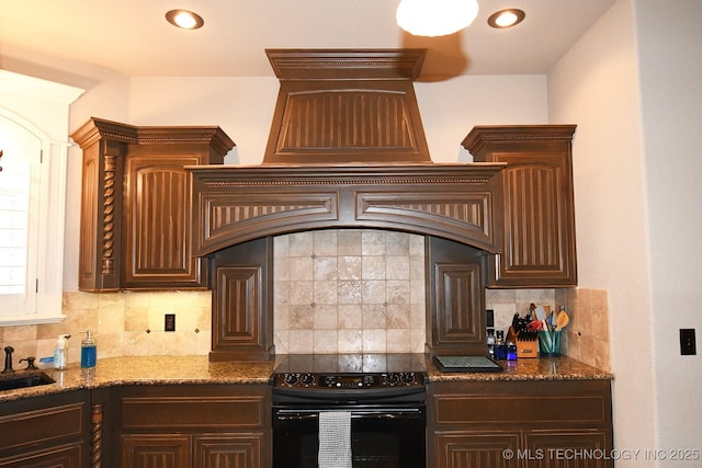 2463 S Park Hl, Tahlequah, OK 74464 - kitchen with black range with electric stovetop, tasteful backsplash, dark brown cabinetry, dark stone counters, and recessed lighting