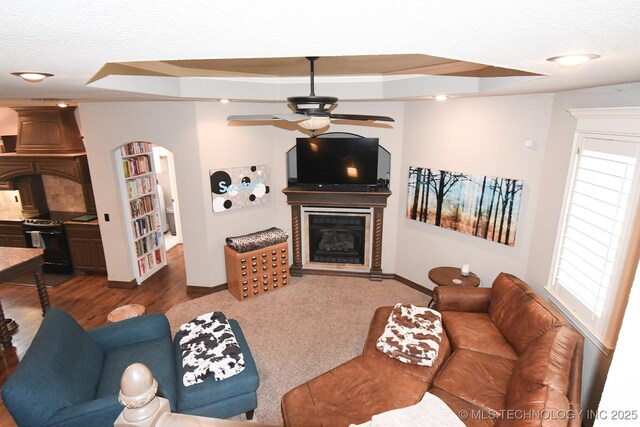 2463 S Park Hl, Tahlequah, OK 74464 - living area with a glass covered fireplace, arched walkways, a ceiling fan, a textured ceiling, and wood finished floors