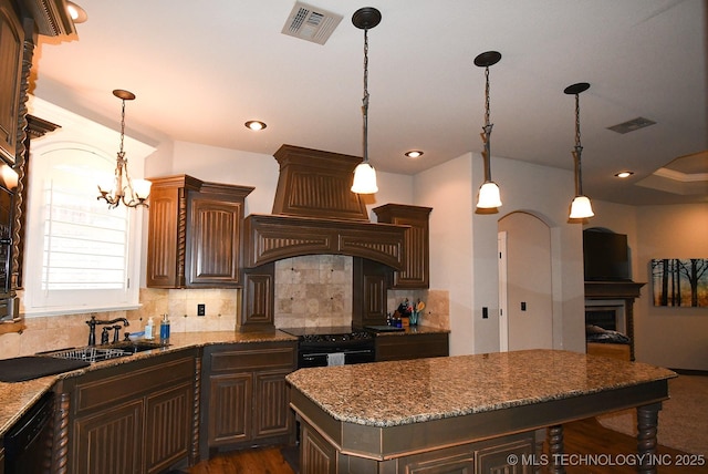 2463 S Park Hl, Tahlequah, OK 74464 - kitchen featuring black appliances, decorative backsplash, a kitchen island, dark stone counters, and a chandelier
