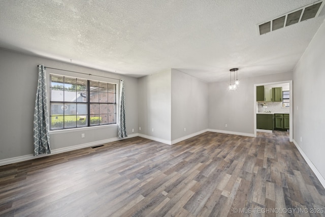 2331 S 99th E Ave, Tulsa, OK 74129 - unfurnished room featuring a textured ceiling, dark wood-style floors, and a chandelier