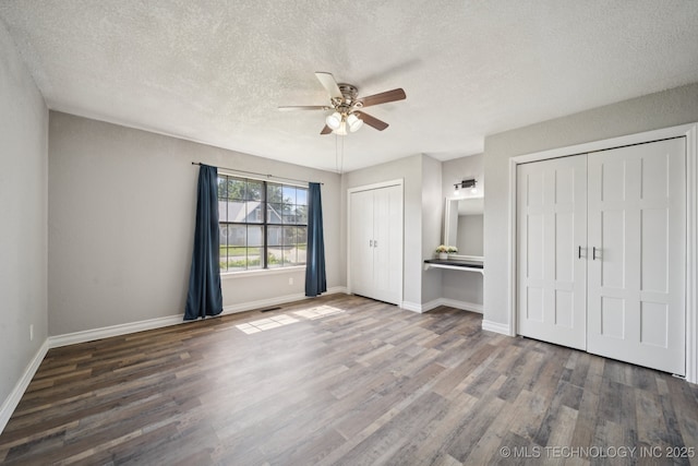 2331 S 99th E Ave, Tulsa, OK 74129 - unfurnished bedroom featuring multiple closets, a textured ceiling, wood finished floors, and ceiling fan