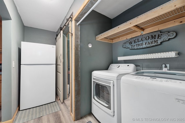 6607 Old Taft Rd, Muskogee, OK 74401 - laundry area featuring independent washer and dryer, a barn door, and light wood-style floors