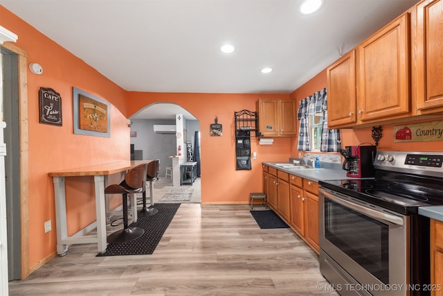 6607 Old Taft Rd, Muskogee, OK 74401 - kitchen featuring electric stove, arched walkways, a wall mounted AC, recessed lighting, and light wood-type flooring