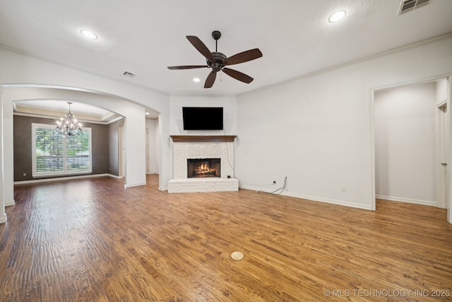 4205 N Narcissus Ave, Broken Arrow, OK 74012 - unfurnished living room featuring crown molding, ceiling fan, a fireplace, wood finished floors, and a chandelier