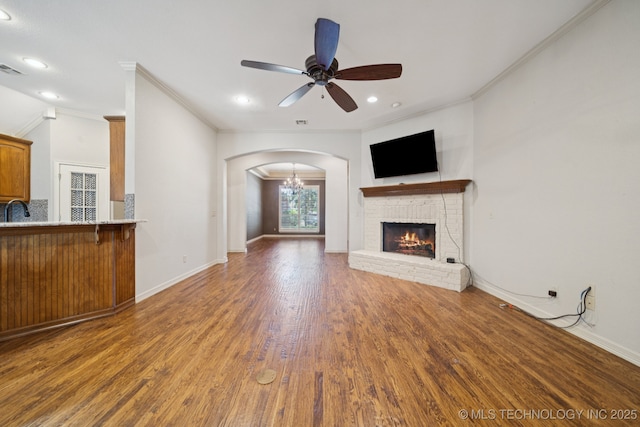 4205 N Narcissus Ave, Broken Arrow, OK 74012 - unfurnished living room with a ceiling fan, crown molding, wood finished floors, a fireplace, and arched walkways