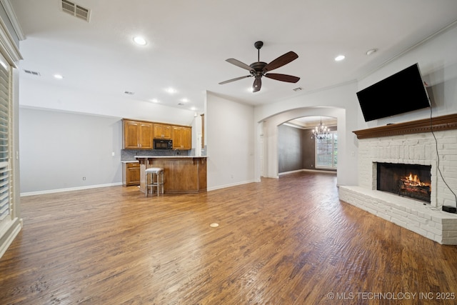 4205 N Narcissus Ave, Broken Arrow, OK 74012 - unfurnished living room with a brick fireplace, ceiling fan, recessed lighting, wood finished floors, and arched walkways