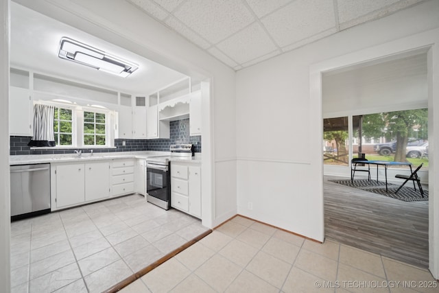 1601 E 6th St, Okmulgee, OK 74447 - kitchen featuring stainless steel appliances, light countertops, light tile patterned floors, decorative backsplash, and white cabinets