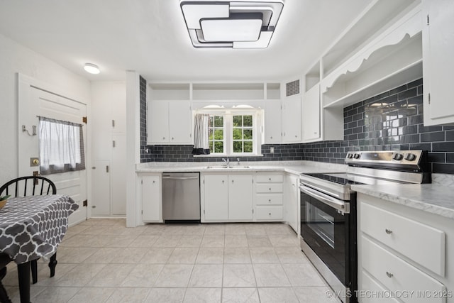 1601 E 6th St, Okmulgee, OK 74447 - kitchen with appliances with stainless steel finishes, tasteful backsplash, light countertops, white cabinets, and light tile patterned floors
