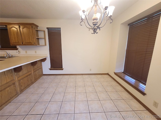 428101 E 1150th Rd, Porum, OK 74455 - kitchen with a chandelier, light countertops, open shelves, brown cabinets, and light tile patterned floors