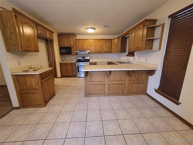 428101 E 1150th Rd, Porum, OK 74455 - kitchen with stainless steel range oven, black microwave, a peninsula, brown cabinetry, and under cabinet range hood