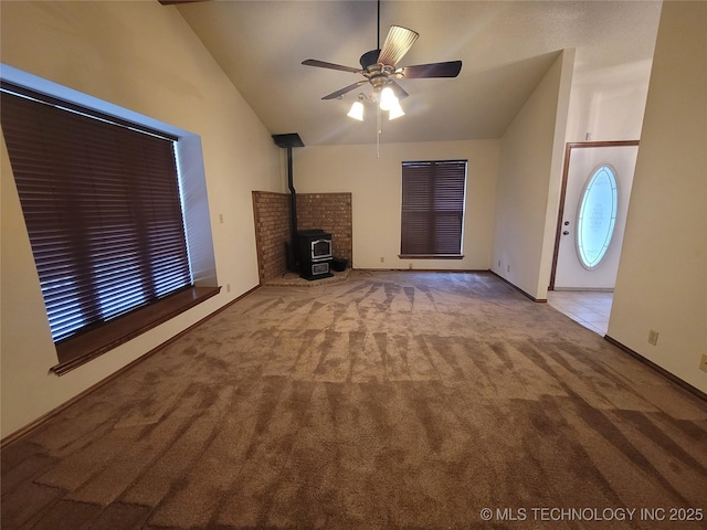 428101 E 1150th Rd, Porum, OK 74455 - unfurnished living room featuring vaulted ceiling, carpet floors, a ceiling fan, and a wood stove
