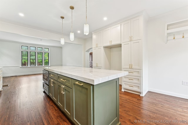 2605 S St Louis Ave, Tulsa, OK 74114 - kitchen featuring white cabinets, arched walkways, dark wood finished floors, light stone counters, and hanging light fixtures