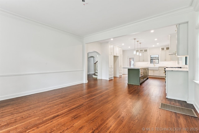 2605 S St Louis Ave, Tulsa, OK 74114 - unfurnished living room with arched walkways, ornamental molding, dark wood-style floors, and recessed lighting