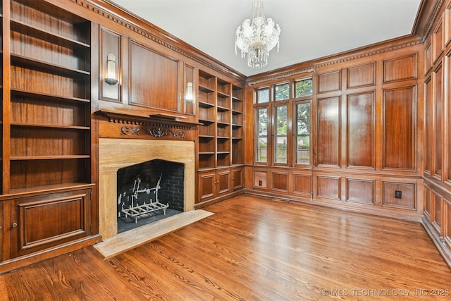 2605 S St Louis Ave, Tulsa, OK 74114 - unfurnished living room with built in shelves, a chandelier, a fireplace, and wood finished floors