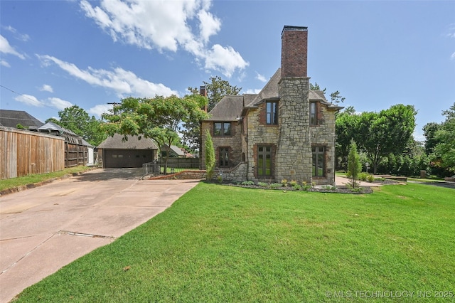 2605 S St Louis Ave, Tulsa, OK 74114 - tudor-style house featuring stone siding, a chimney, and a garage