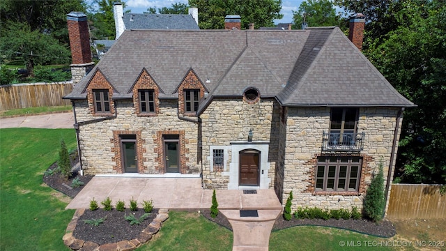 2605 S St Louis Ave, Tulsa, OK 74114 - french country style house featuring a chimney, stone siding, and roof with shingles