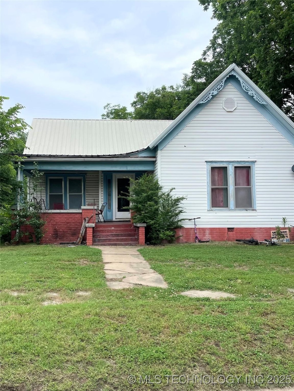 403 E 6th St, Pawhuska, OK 74056 - view of front of property with covered porch, a front yard, and a metal roof