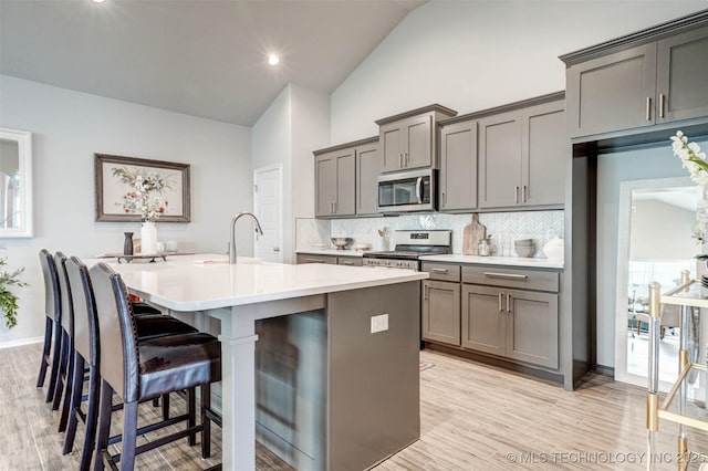 1914 W Imperial St, Broken Arrow, OK 74011 - kitchen featuring stainless steel appliances, gray cabinets, a center island with sink, tasteful backsplash, and high vaulted ceiling
