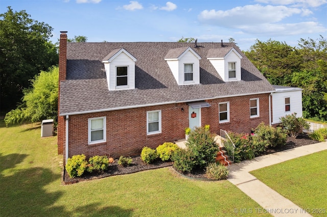 1210 E 15th St, Ada, OK 74820 - new england style home featuring brick siding, a chimney, a front lawn, and roof with shingles
