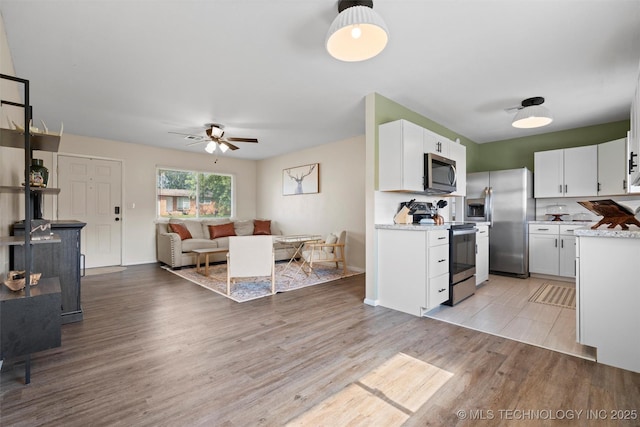 321 NE Elmhurst Ave, Bartlesville, OK 74006 - kitchen with appliances with stainless steel finishes, light countertops, open floor plan, white cabinets, and light wood finished floors
