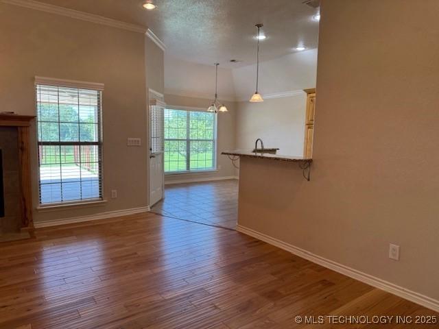 9 Arrowhead, Burneyville, OK 73430 - unfurnished living room featuring a chandelier, crown molding, a fireplace, wood finished floors, and recessed lighting