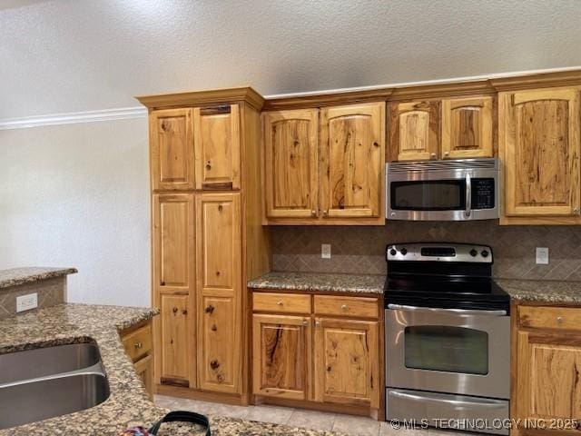 9 Arrowhead, Burneyville, OK 73430 - kitchen with stainless steel appliances, dark stone countertops, tasteful backsplash, brown cabinets, and crown molding