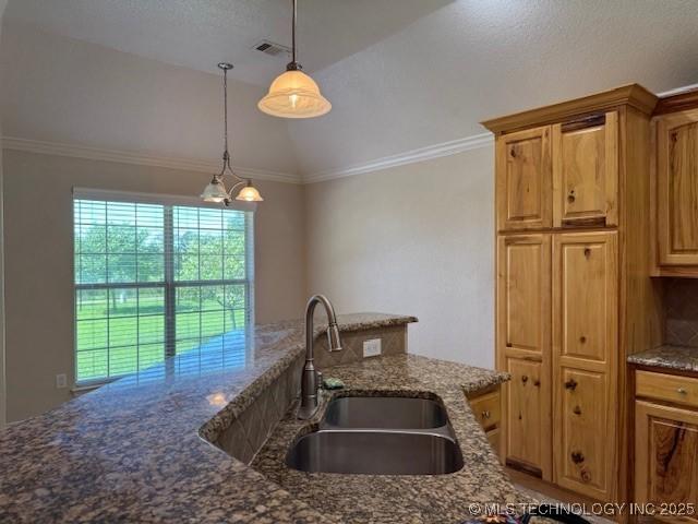 9 Arrowhead, Burneyville, OK 73430 - kitchen with pendant lighting, lofted ceiling, dark stone countertops, crown molding, and brown cabinetry