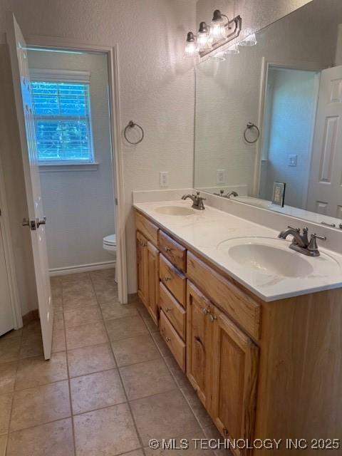 9 Arrowhead, Burneyville, OK 73430 - bathroom featuring double vanity, tile patterned flooring, and a textured wall