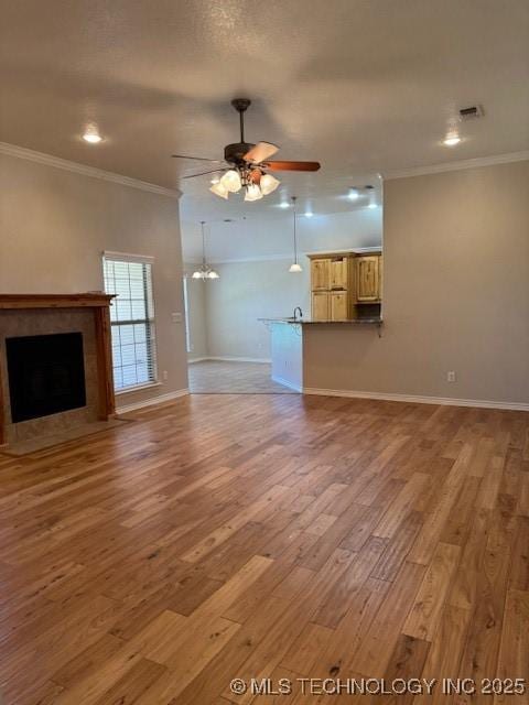 9 Arrowhead, Burneyville, OK 73430 - unfurnished living room featuring ceiling fan, crown molding, a premium fireplace, light wood-type flooring, and a chandelier