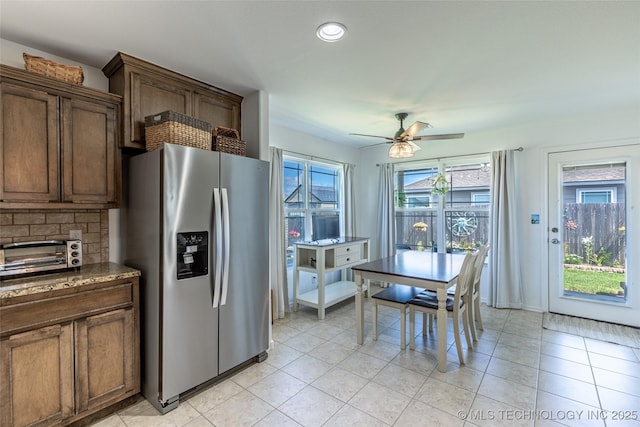 11042 N 120th Ave E, Owasso, OK 74055 - kitchen featuring stainless steel fridge with ice dispenser, ceiling fan, light tile patterned floors, backsplash, and dark stone countertops