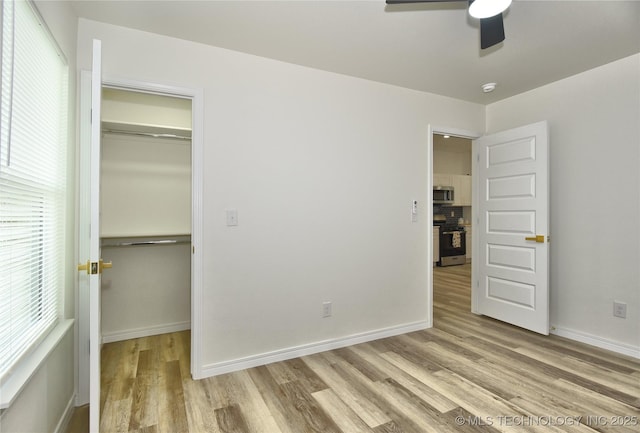 217 E Virgin St, Tulsa, OK 74106 - unfurnished bedroom featuring wood finished floors, a closet, multiple windows, and a spacious closet