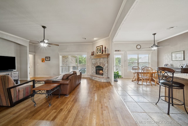 8483 N 68th E Ave, Owasso, OK 74055 - living area with a ceiling fan, a stone fireplace, crown molding, and light wood-style floors