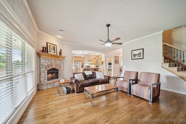 8483 N 68th E Ave, Owasso, OK 74055 - living room featuring a ceiling fan, stairway, wood finished floors, a stone fireplace, and crown molding