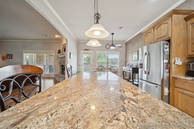 8483 N 68th E Ave, Owasso, OK 74055 - kitchen featuring stainless steel refrigerator with ice dispenser, light stone counters, a fireplace, hanging light fixtures, and ornamental molding
