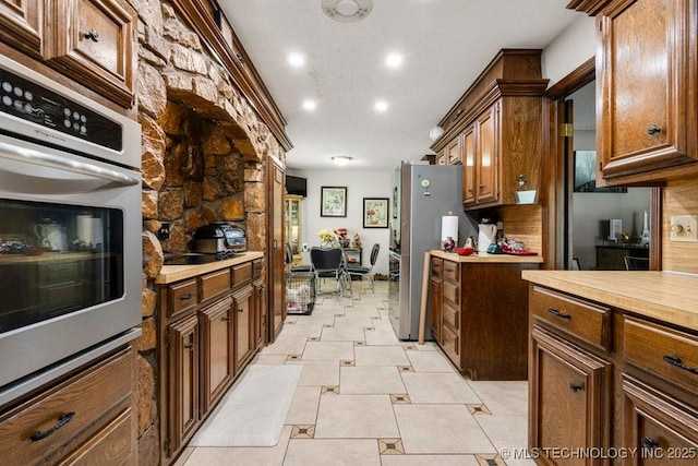2528 W Commercial St, Broken Arrow, OK 74012 - kitchen with stainless steel appliances, light countertops, recessed lighting, and brown cabinetry