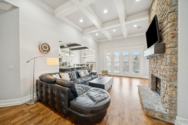 905 W Elmira St, Broken Arrow, OK 74012 - living area featuring beam ceiling, arched walkways, a stone fireplace, wood finished floors, and a chandelier