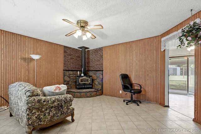 16429 E 1st St, Tulsa, OK 74108 - office area featuring a wood stove, wood walls, a textured ceiling, a ceiling fan, and light tile patterned floors