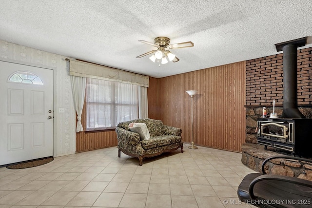 16429 E 1st St, Tulsa, OK 74108 - entryway with a wood stove, ceiling fan, a textured ceiling, wood walls, and light tile patterned flooring