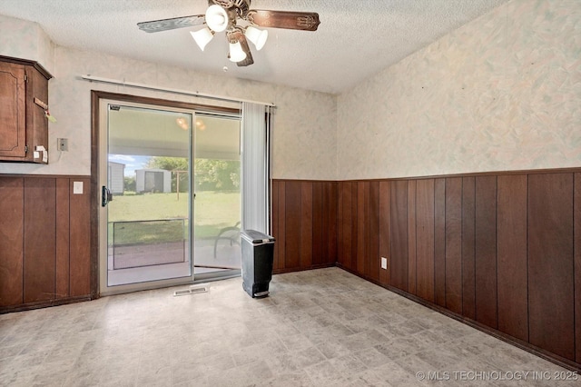 16429 E 1st St, Tulsa, OK 74108 - empty room with wainscoting, a textured ceiling, ceiling fan, wood walls, and light flooring