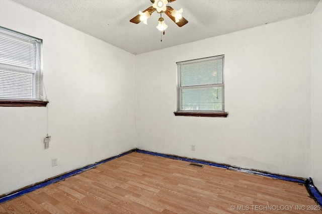 16429 E 1st St, Tulsa, OK 74108 - empty room with a ceiling fan, wood finished floors, plenty of natural light, and a textured ceiling