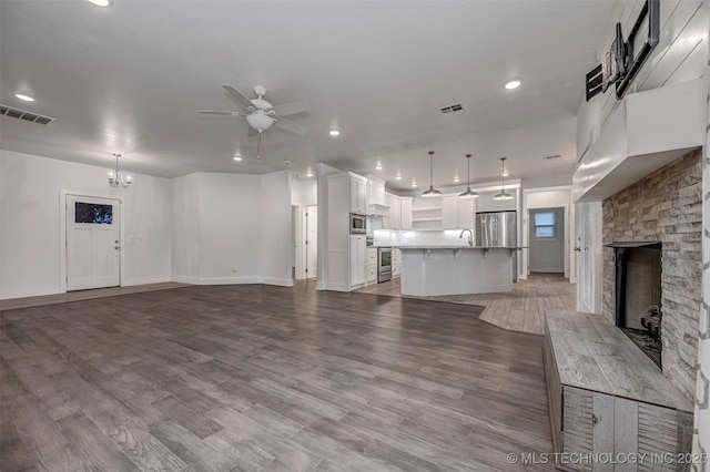 1341 Alvera Ln, Wynnewood, OK 73098 - unfurnished living room with a ceiling fan, a fireplace, wood finished floors, recessed lighting, and a chandelier