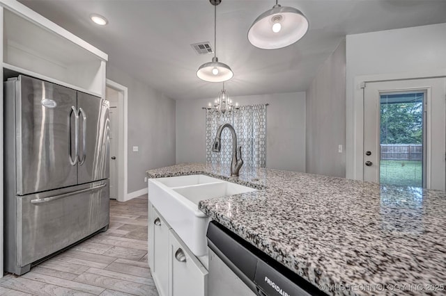 1341 Alvera Ln, Wynnewood, OK 73098 - kitchen with stainless steel appliances, white cabinetry, light stone counters, a chandelier, and light wood-type flooring