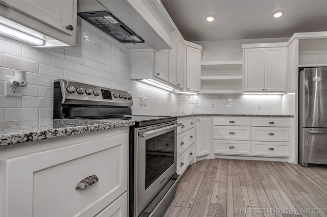 1341 Alvera Ln, Wynnewood, OK 73098 - kitchen with stainless steel appliances, range hood, open shelves, backsplash, and white cabinetry
